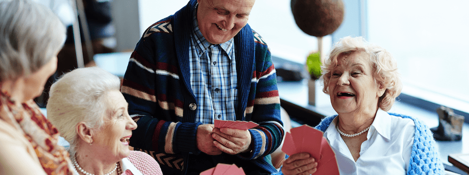 elderly group sitting around laughing, playing cards; adjusting to retirement