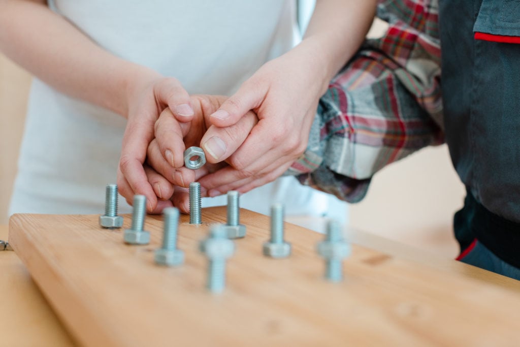 Closeup of man in occupational therapy screwing nut on bolt; benefits of occupational therapy