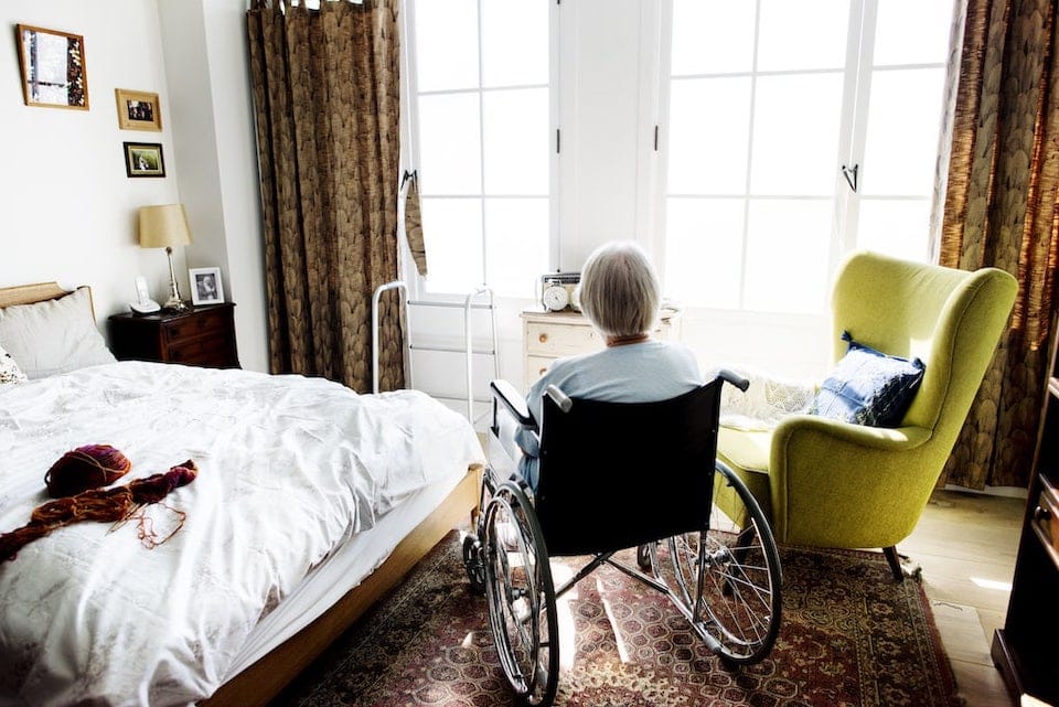 elderly woman sitting in a wheelchair in her room looking lonely; assisted living placement agencies
