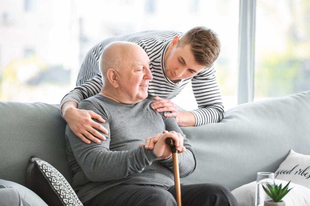 young man tending to an elderly man dealing with dementia symptoms