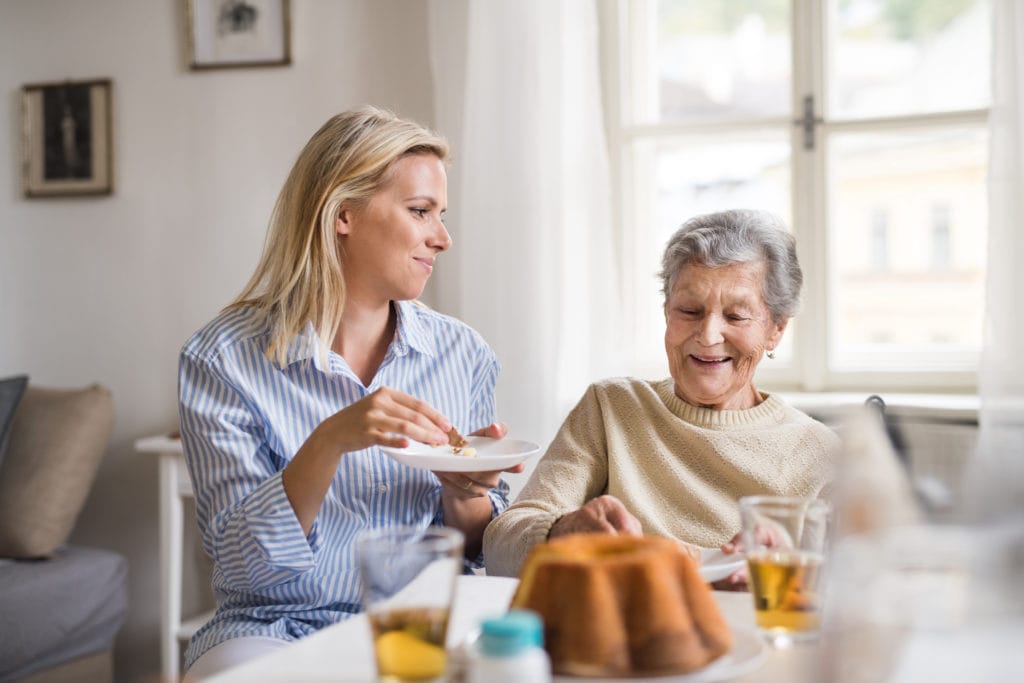 young woman helping a senior woman eat