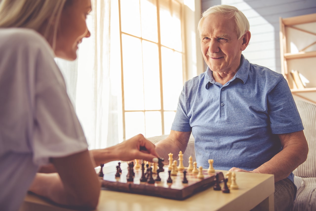 a volunteer at a nursing home playing chess with a resident