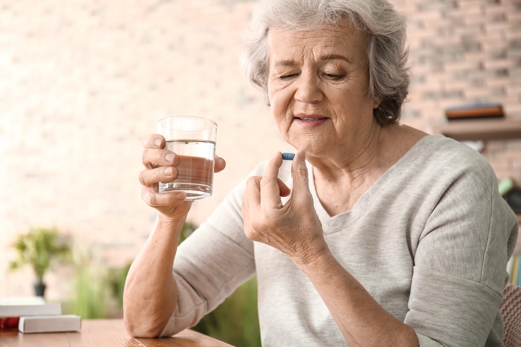 Elderly woman taking pill at home