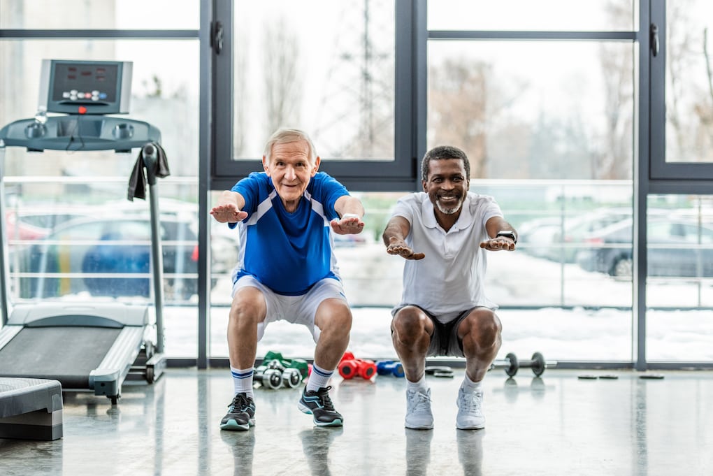 two senior men doing squats at a gym in a 55+ community in Minnesota