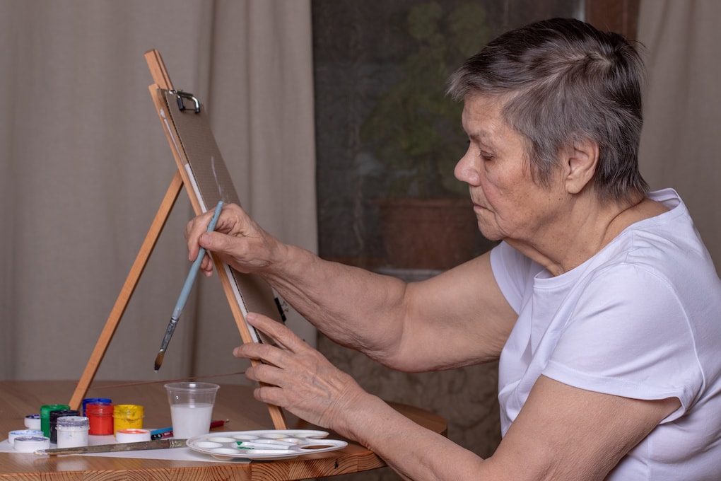  woman paints a picture at home as one of the activities for people with dementia