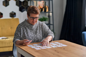 senior woman with dementia playing solitaire at home.