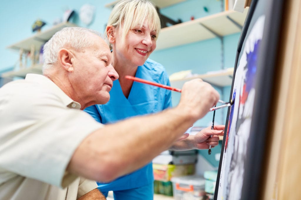 senior man with dementia does art therapy for cognitive exercise