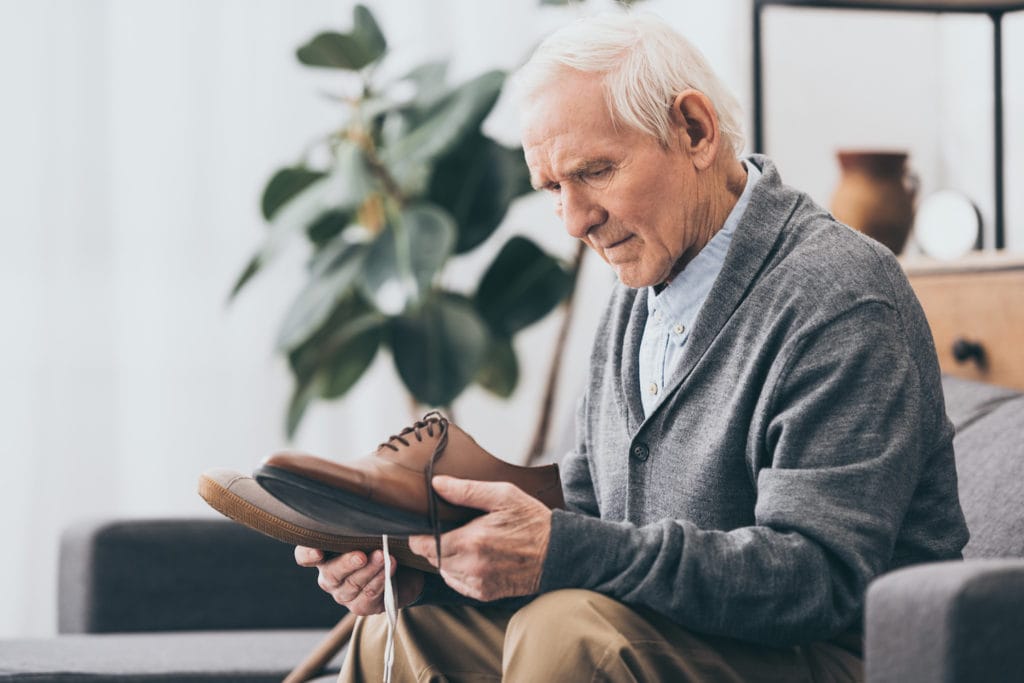 senior man looking at shoes in confusion early stages of dementia