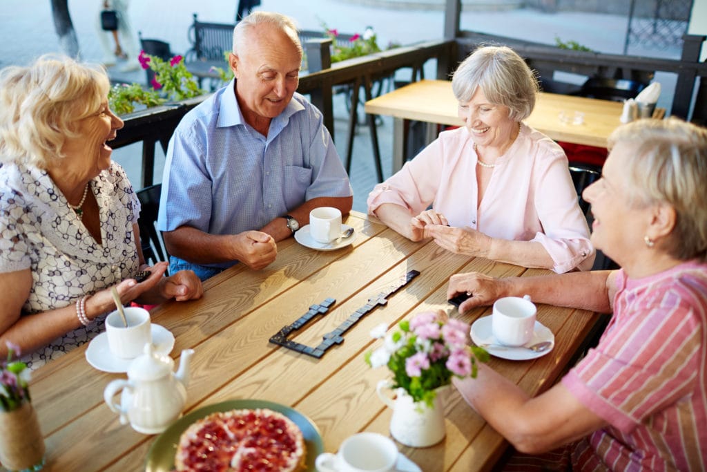 group of elderly friends playing dominos for their cognitive exercise for dementia