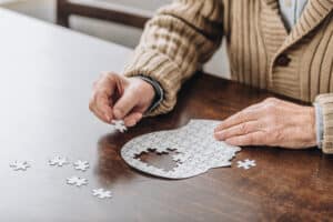cropped view of senior man playing with puzzles what are the signs of end stage dementia watching for symptoms