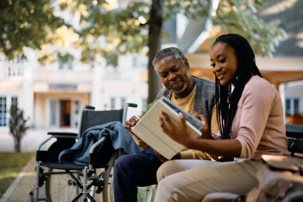 black woman and man looking at photo book at memory care facility