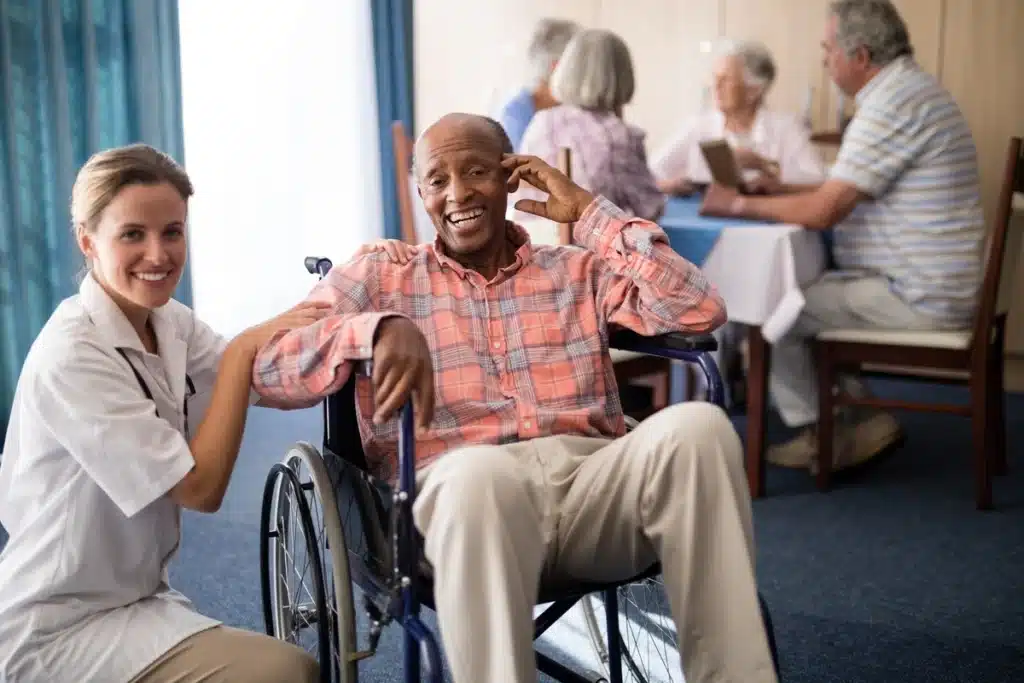 smiling elderly man and caregiver at nursing home
