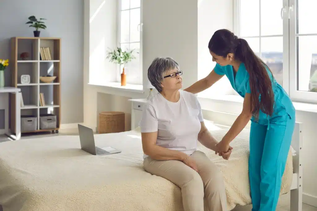 caregiver helping to the elderly woman in her room