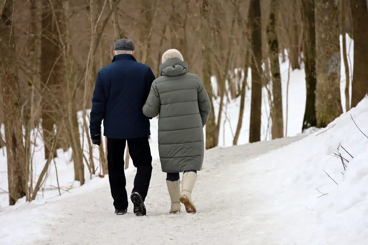 Older couple takes a walk through snowy woods