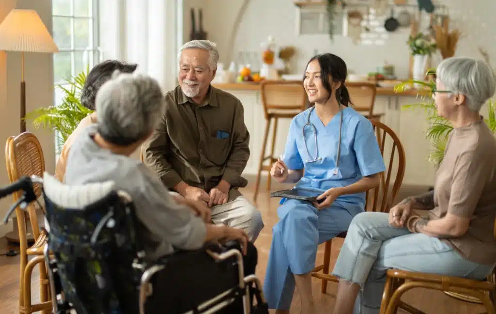 A group sits in a circle at an assisted living facility talking with a nurse