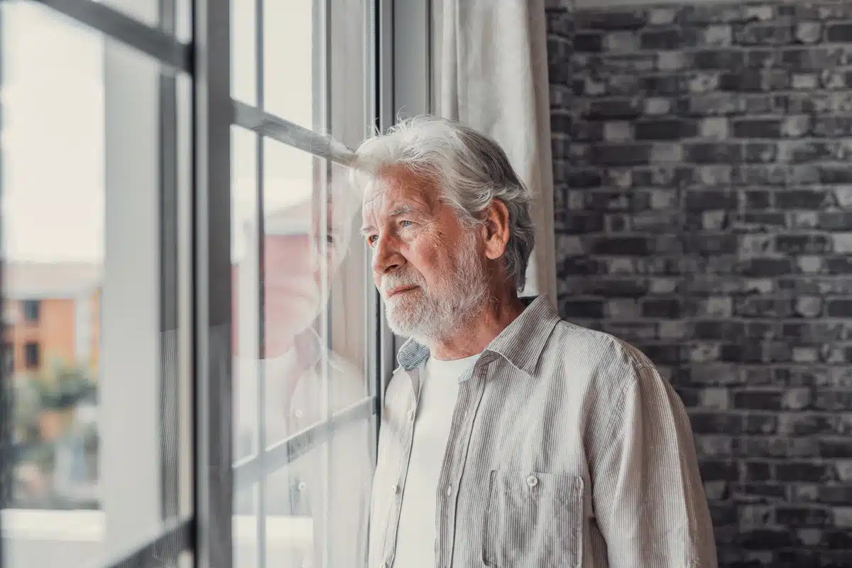 elderly man stares out window