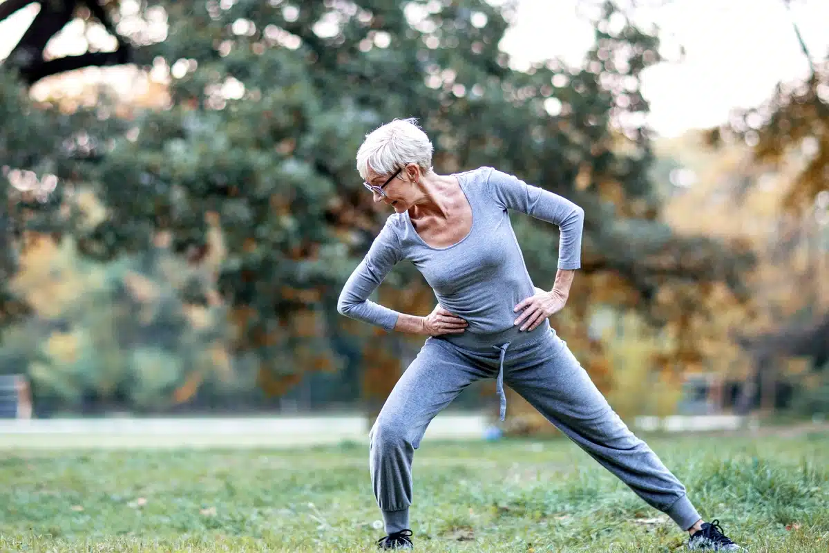 Older woman performs leg strengthening exercises for seniors in the park