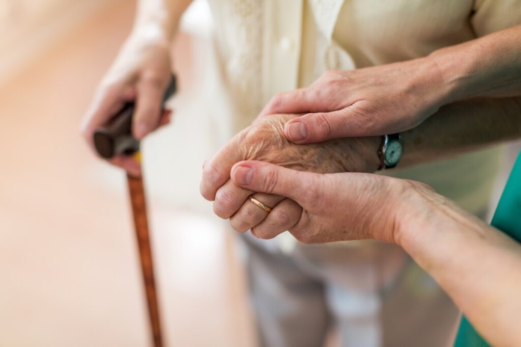 Nurse holding elderly woman's hand