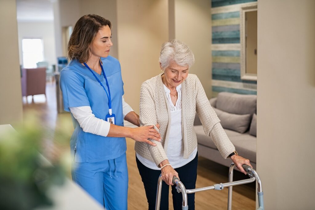 nurse helping old woman to walk at nursing home with walker