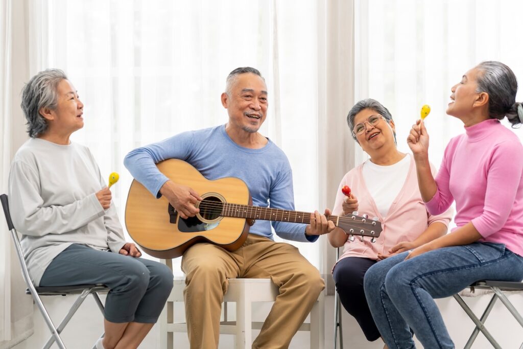 man playing guitar for group of senior citizens