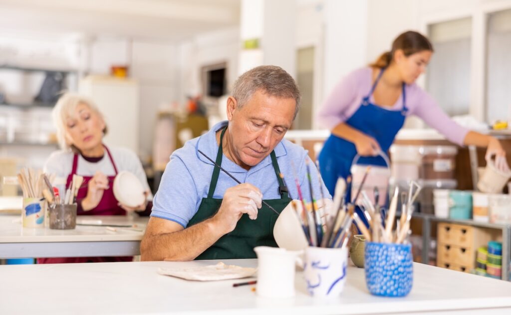 Older man painting pottery