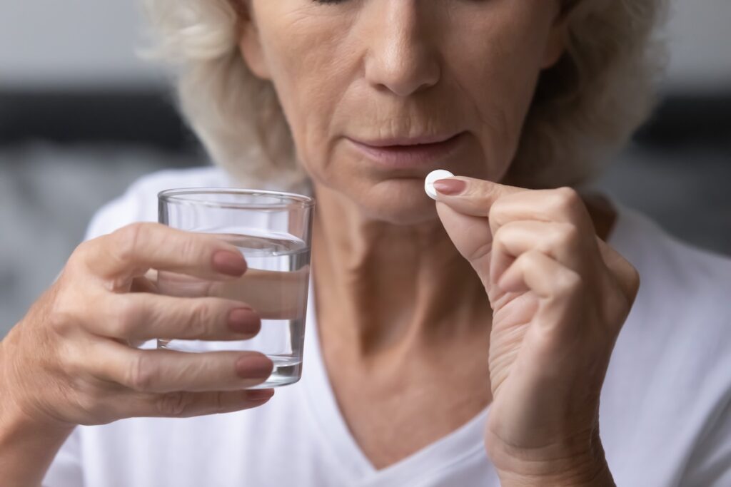 Mature senior lady taking pills for relieving mental disease