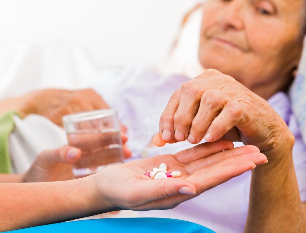 Homecare nurse helping elderly lady to take her daily medicine.