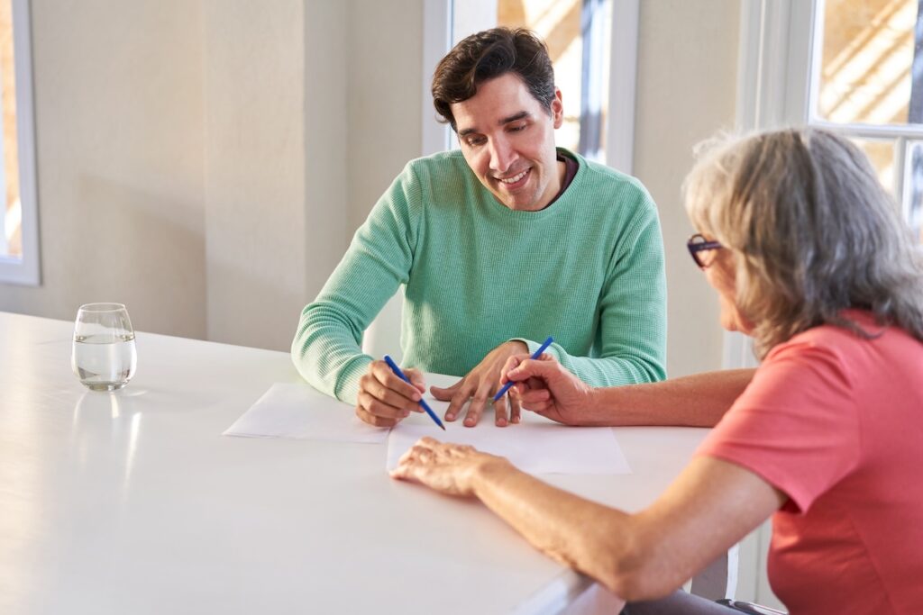 Son helps senior woman fill out contract at home